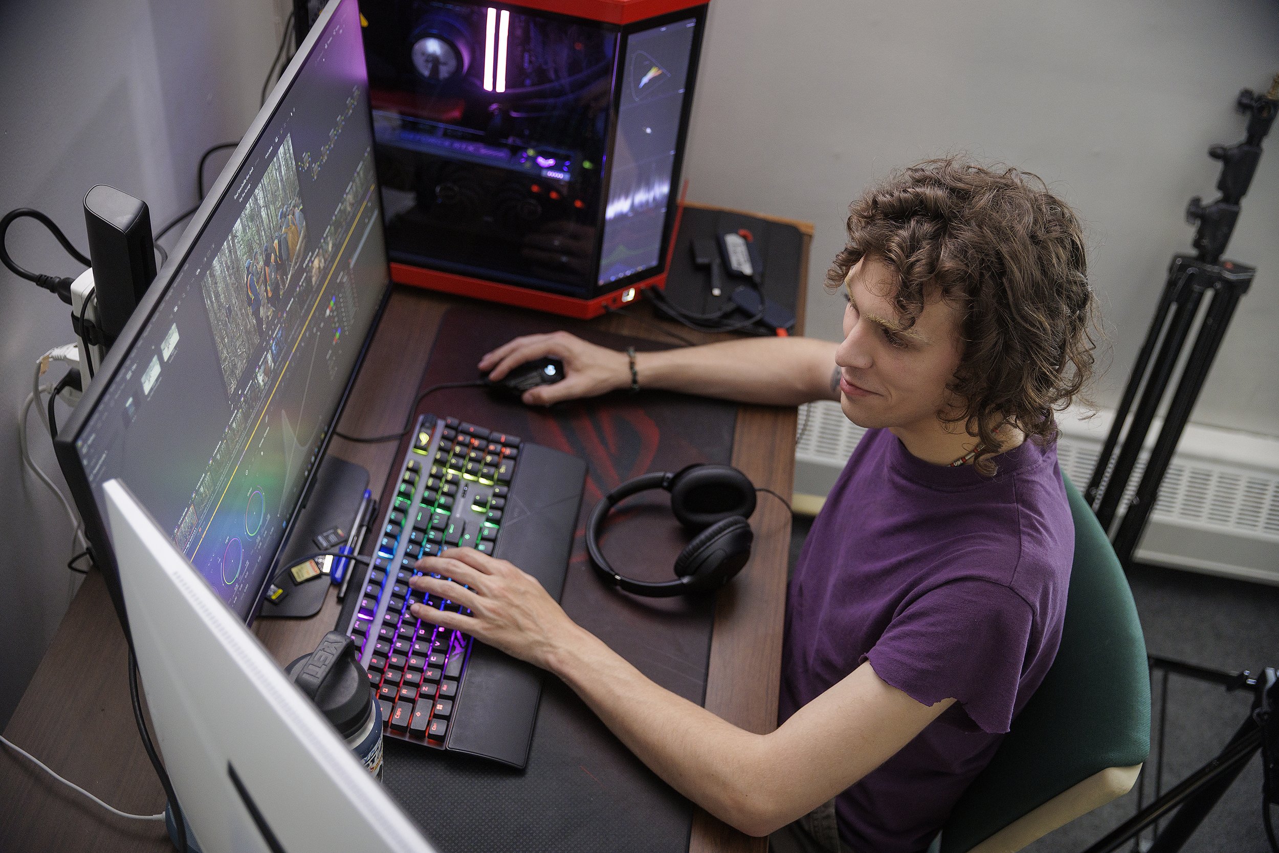 Ben sits at a computer desk with two monitors