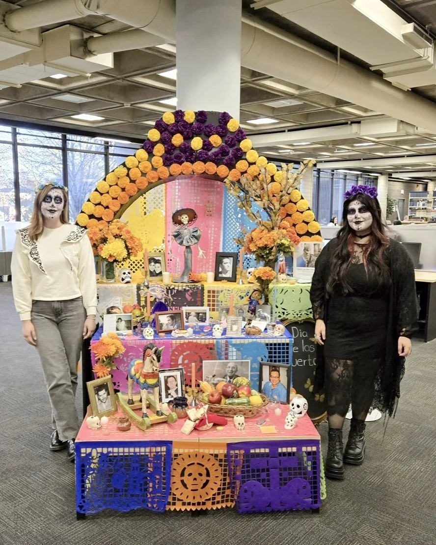 Melissa in traditional facepaint stands next to an altar in the library