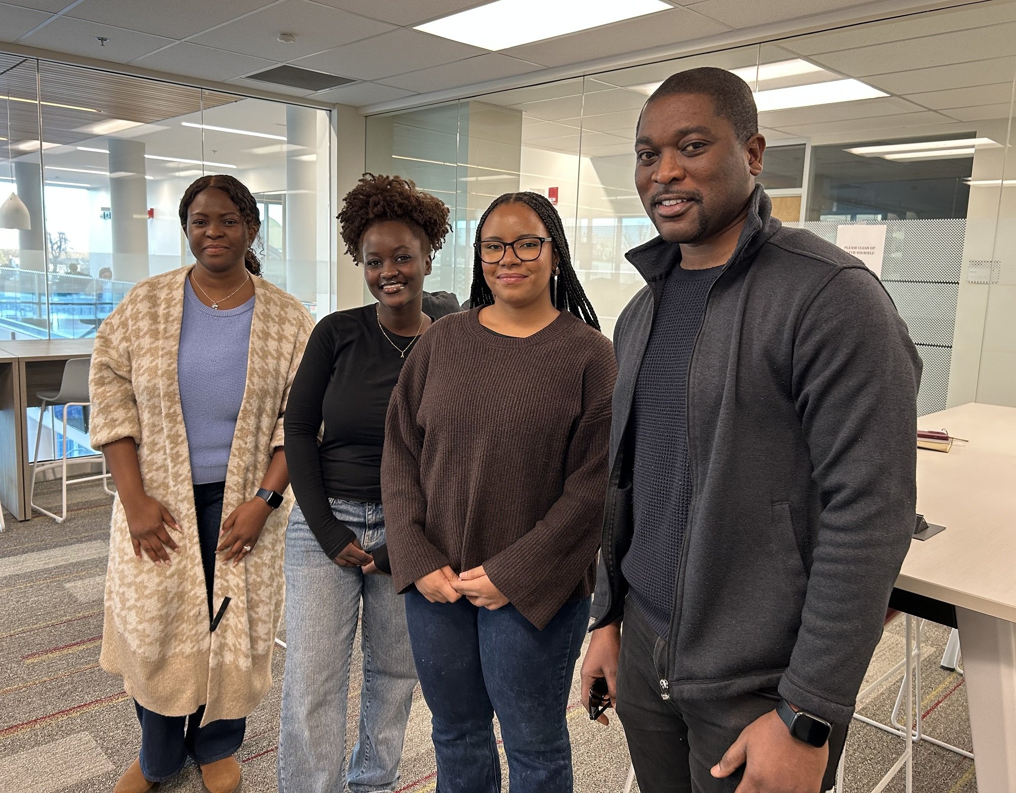 A man stands with three students in a SMU classroom