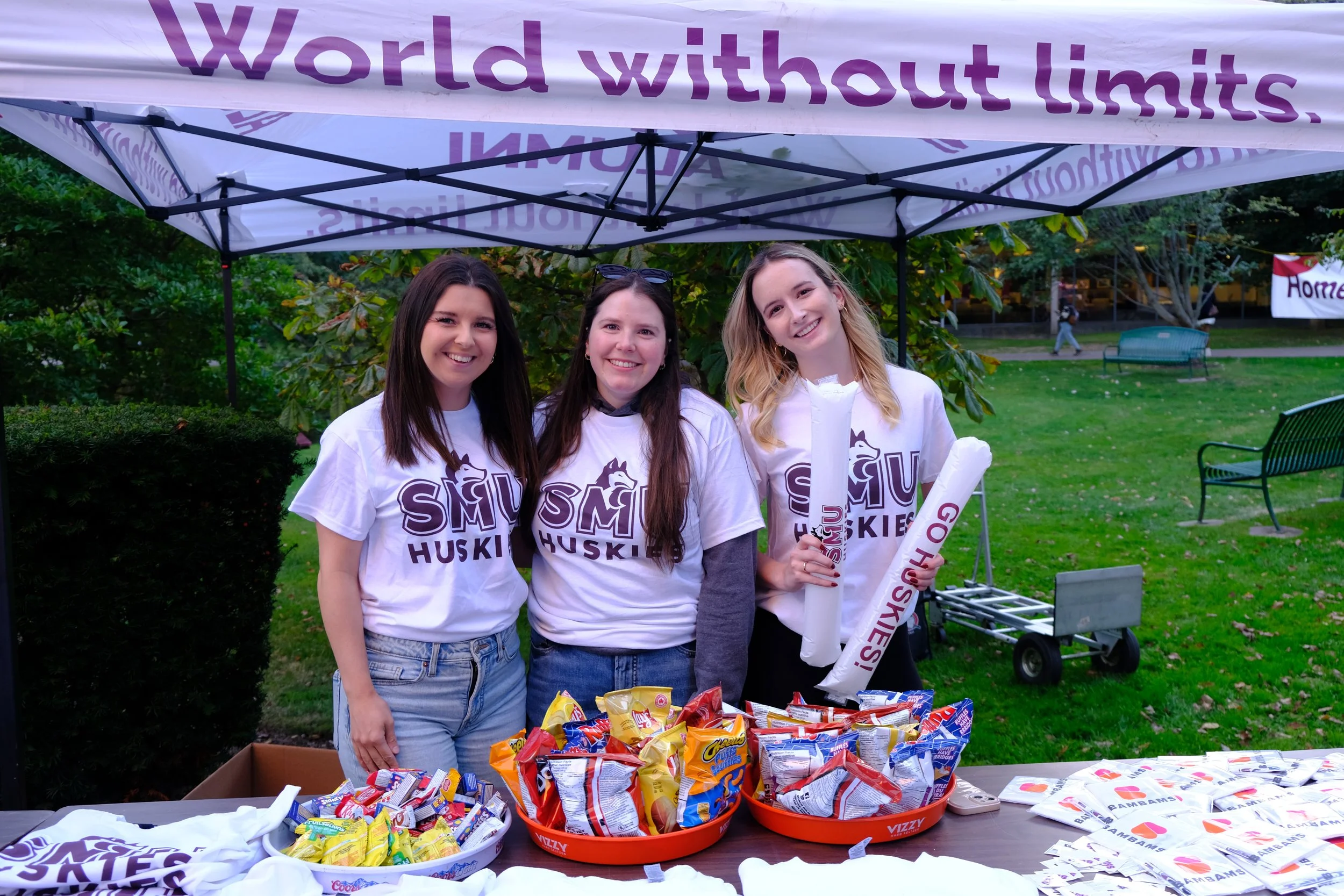 Maddie and two volunteers wear SMU Huskies shirts at an event