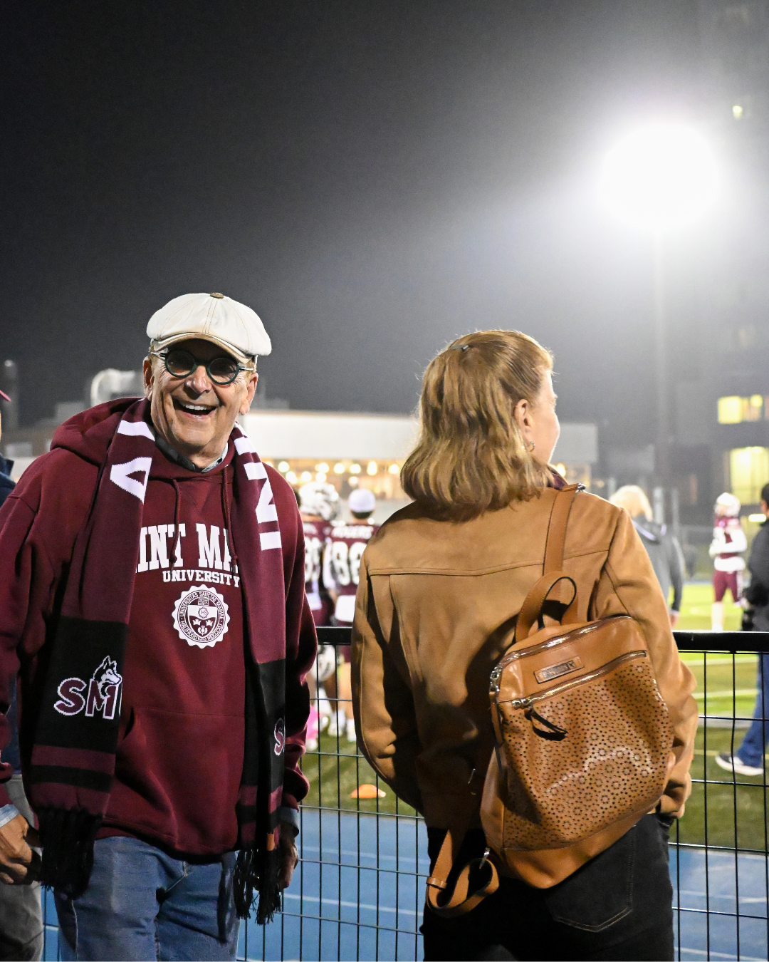 William smiles while standing at the Huskies stadium during a nighttime football game