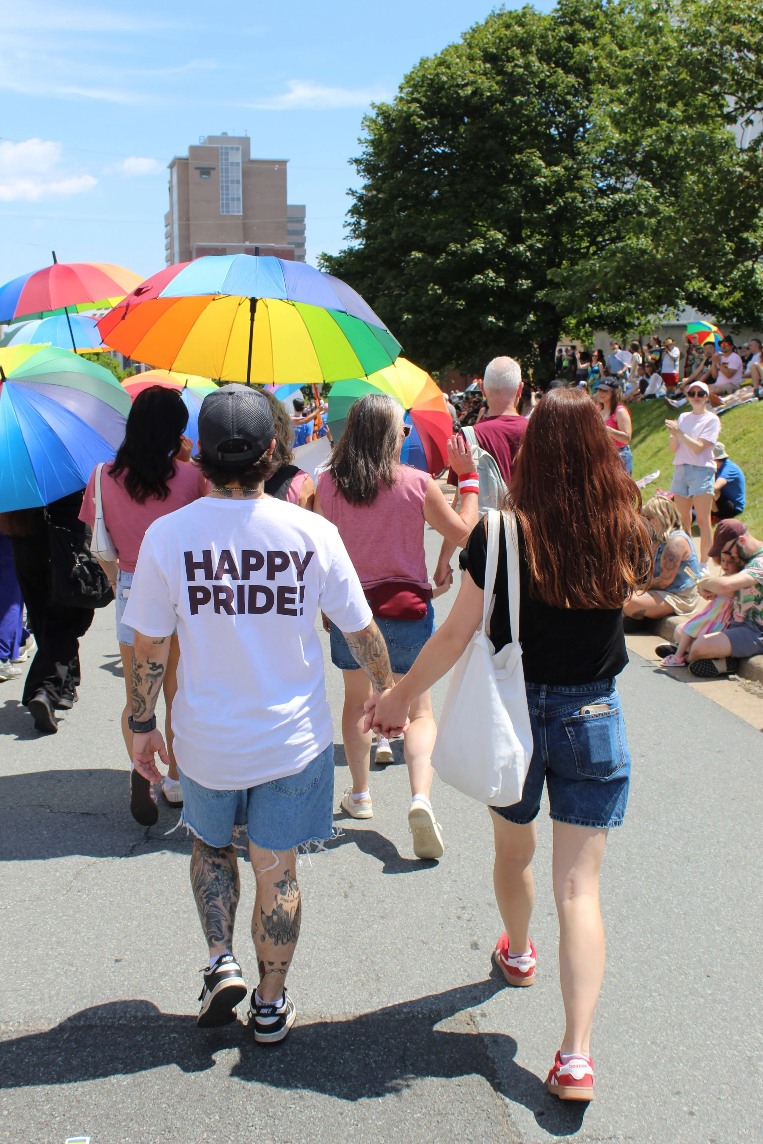 Two people hold hands and walk in the pride parade