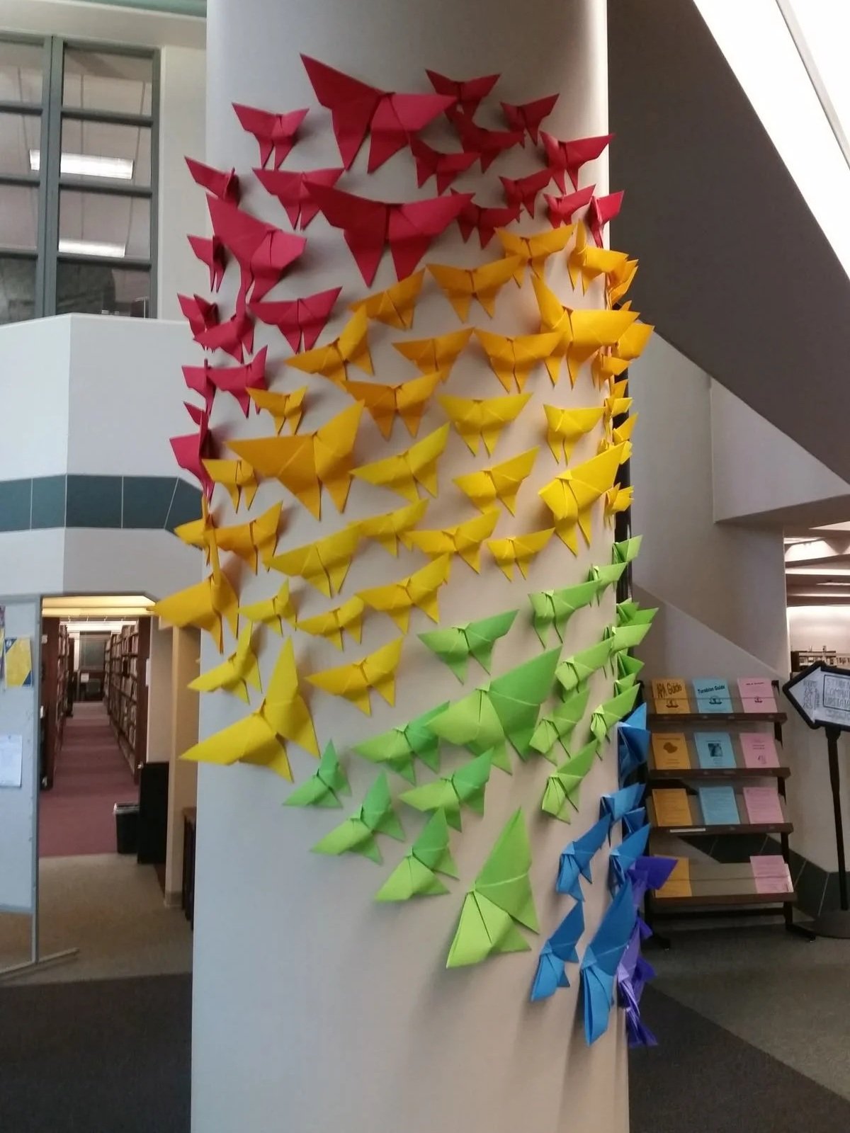 Origami butterflies arranged in rainbow colours on a pole