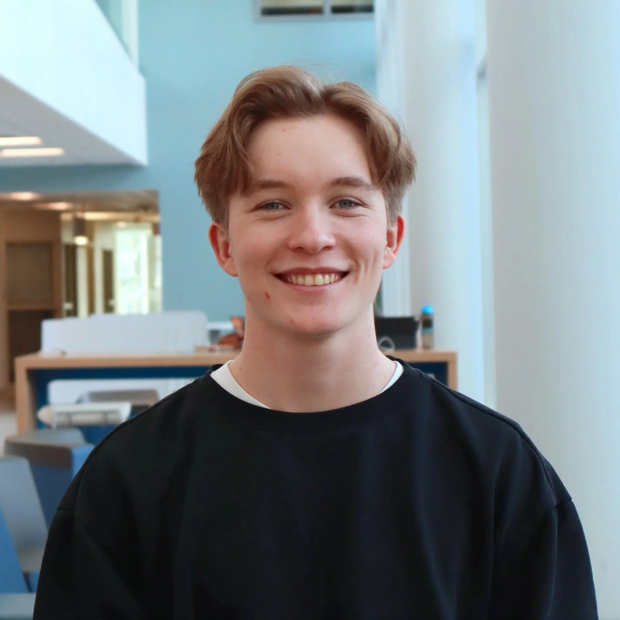 Noah is a young white man with blond hair. He wears a black sweater.