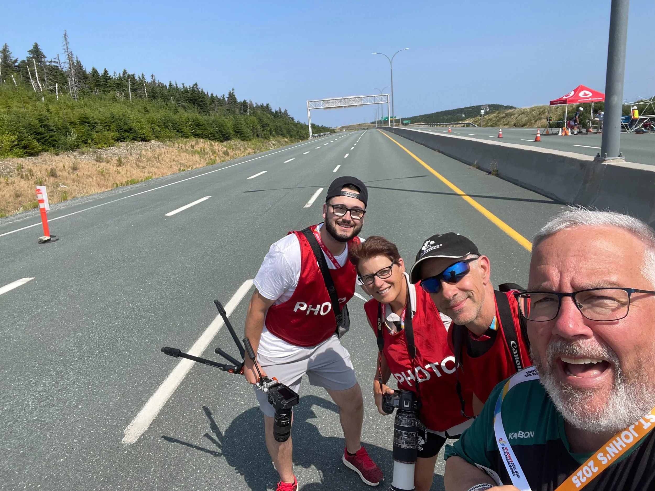 Four people in Photo jerseys pose together on a road