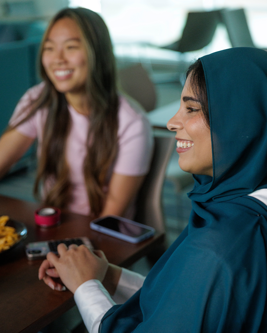 Two female students smile in conversation
