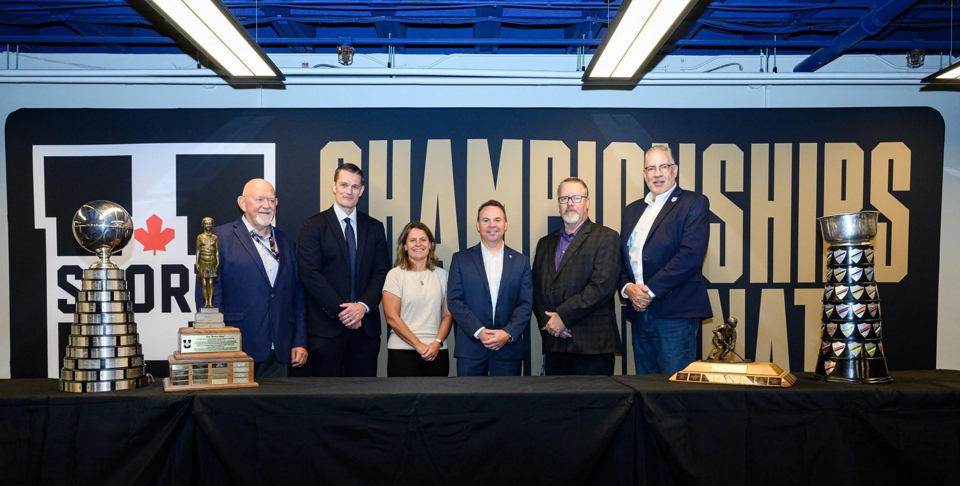 A group of people pose in front of a U Sports banner