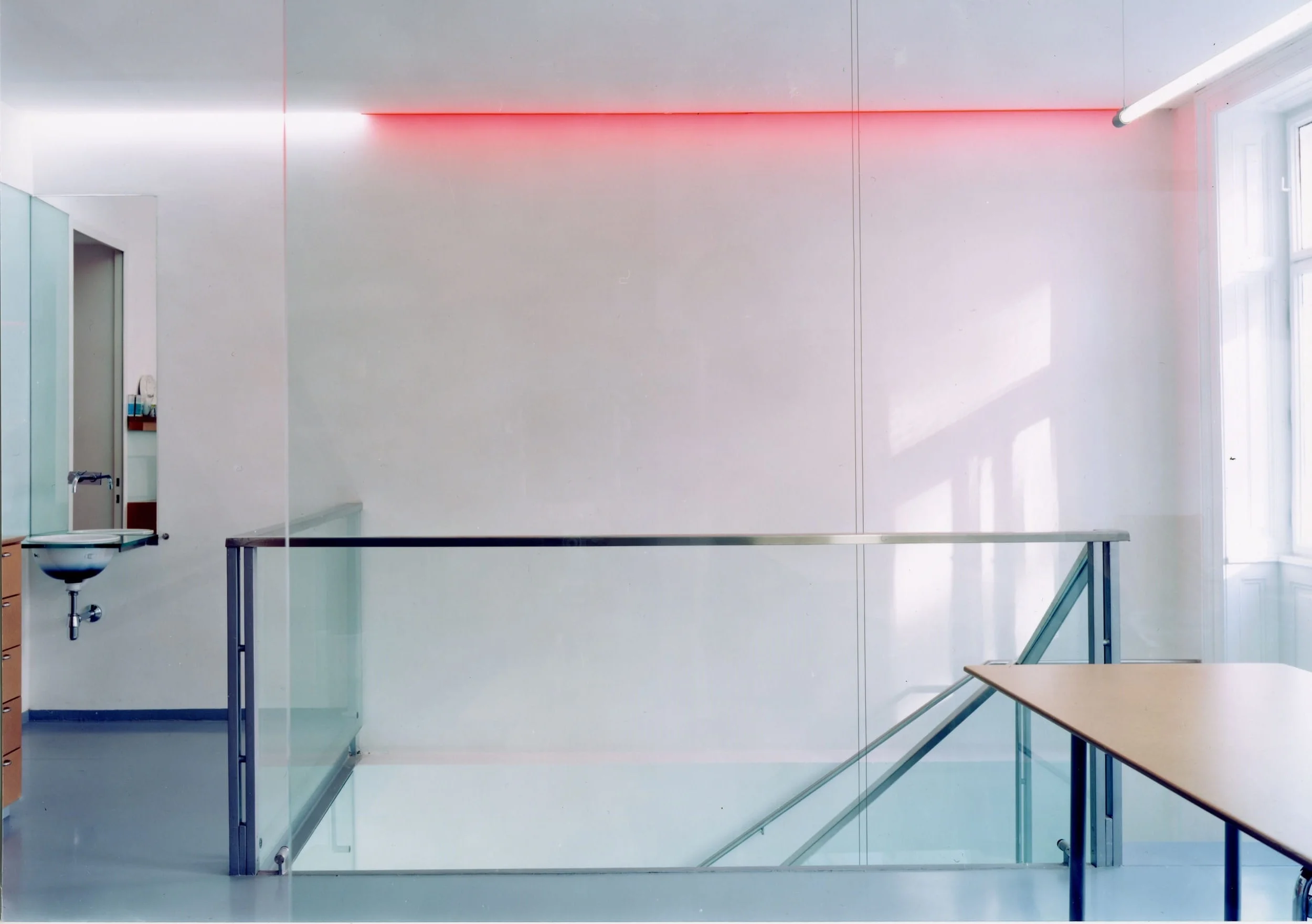  ... teeküche und aufenthaltsraum an der stiegengalerie werden durch ein rotoranges neonband in der decke zu einer kontemplativen entspannungszone, die auch eine starke verbindung nach unten wahrt 