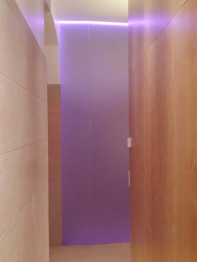  umbau eines kellerraums zu einem barrierfrei benützbaren wellness-bereich mit infrarot-kabine, großer dusche und wc. der einsatz von ahorn bei der möblierung, großformatigen hellen fliesen und led-bändern mit wechselnden farben bewirkt eine angenehm