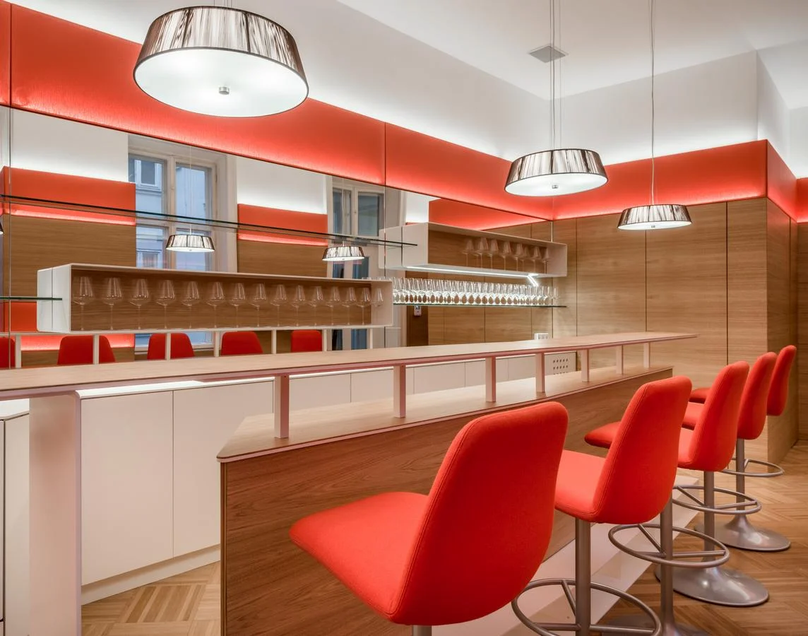 In einer alten Büroetage (um 1900 erbaut) wird ein langgezogener Abstellraum, in einen repräsentativen Bar / Lounge - Bereich für 30-40 Personen umgewandelt. In einladender Atmosphäre soll, nach größeren Sitzungen und Versammlungen, ein informeller Gedankenaustausch gefördert werden. Auch kleinere Gruppen von 8-10 Personen können sich hier treffen und finden in einer intimeren Sitzzone Raum zur Kommunikation.
