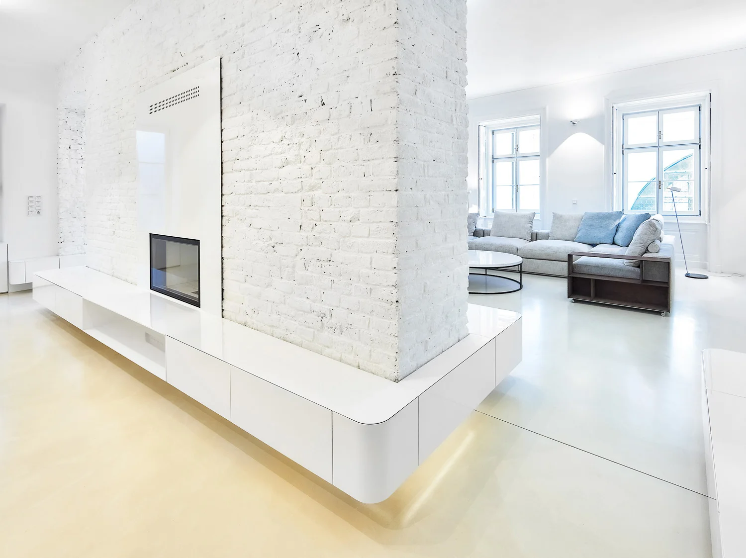  Fixe Möblierungen in schlichtem, zurückhaltendem Design stärken vorrangig den Raumentwurf und schaffen Stauraum. Beispielgebend dafür ein, um die Sichtziegelwand rundum laufendes Sideboard, das in seiner Linienführung und Detailausarbeitung jedoch e