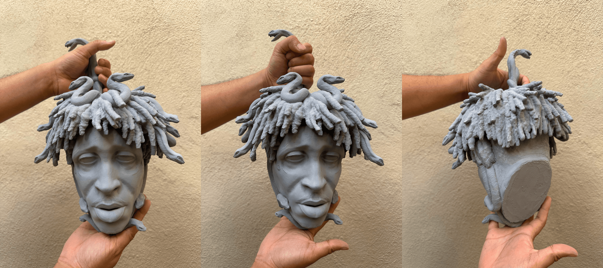 A person's hand holding a gray sculpture of a human face with dreadlock hair, featuring snake figures intertwined in the hair, shown from three angles.