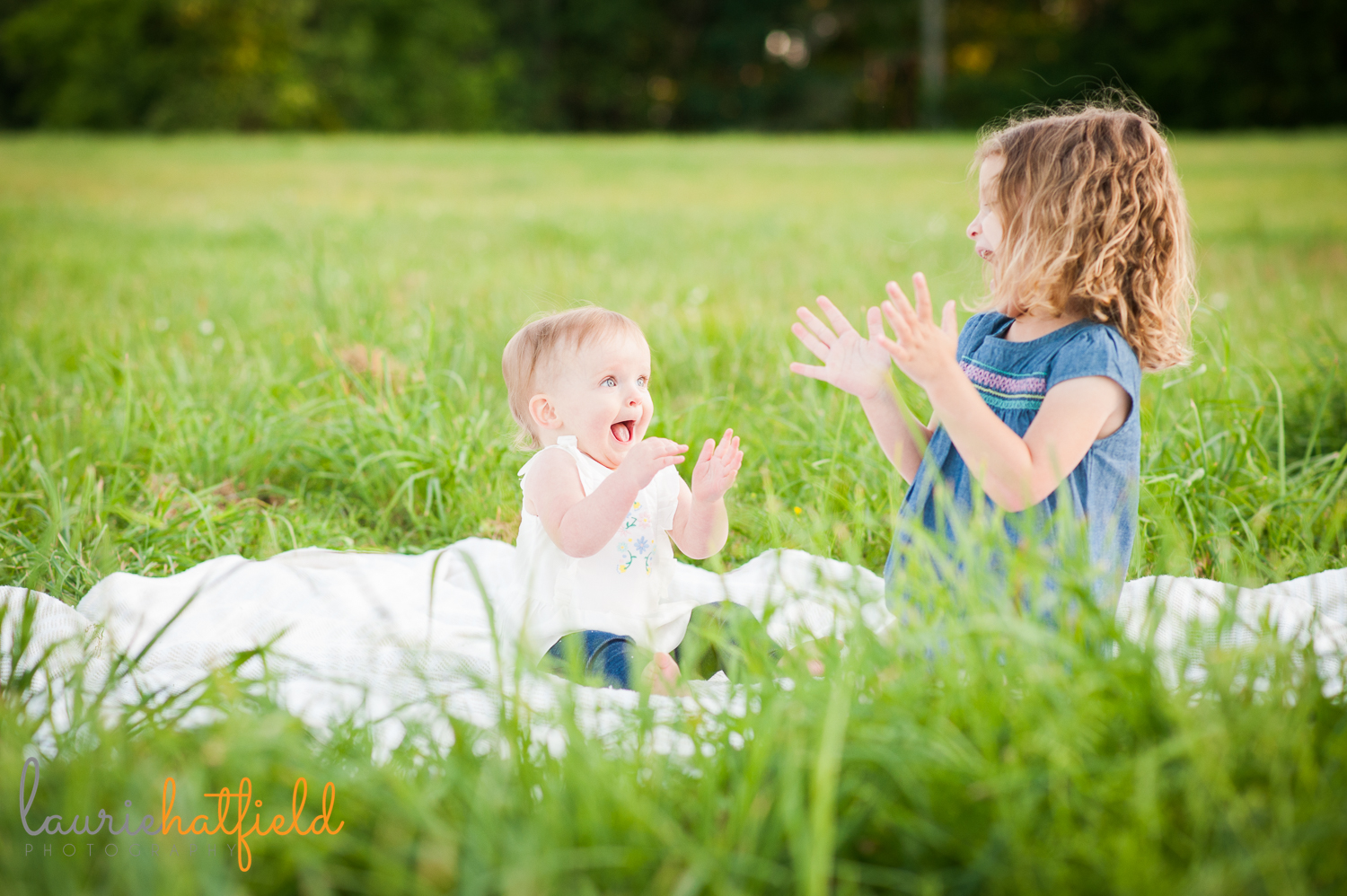 sisters clapping in grass | Huntsville family photographer