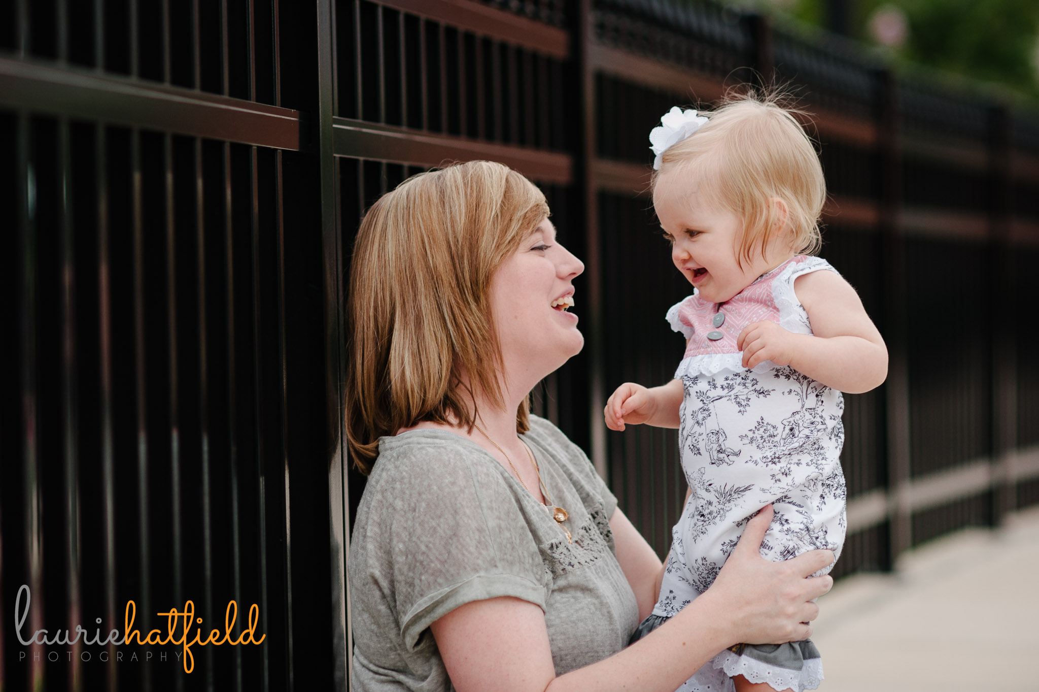 mom and one year old baby sitting against fence | Mobile AL photographer