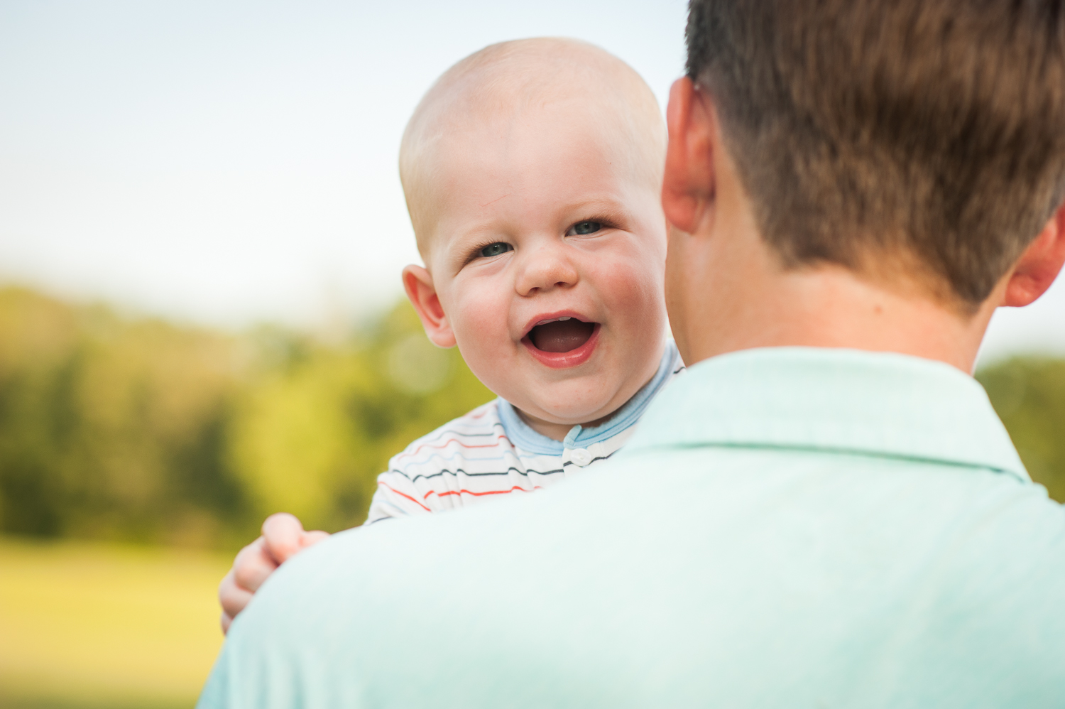 baby boy laughing over dad's shoulder | Mobile photographer