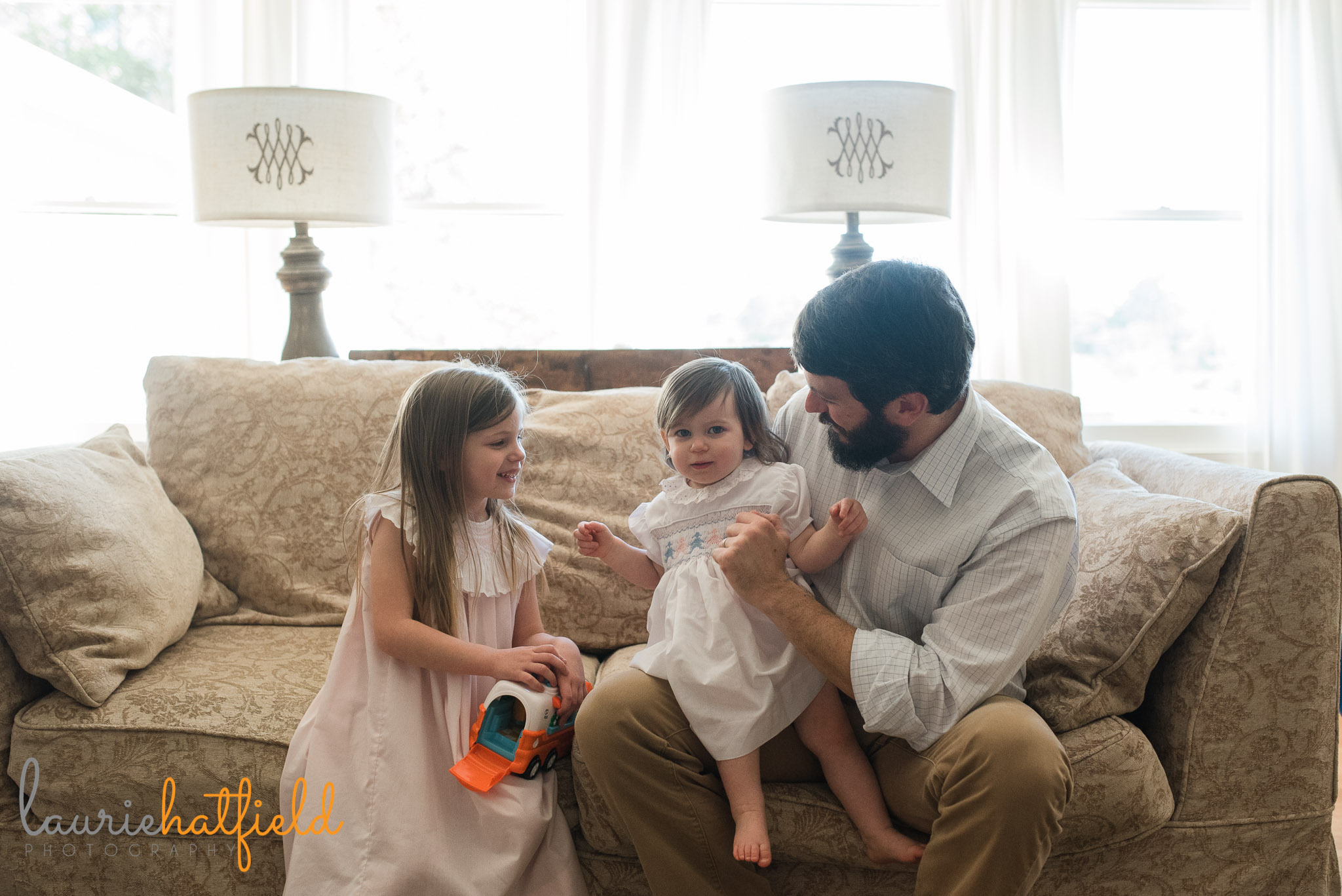 dad with 2 daughters on sofa | Mobile lifestyle newborn photographer