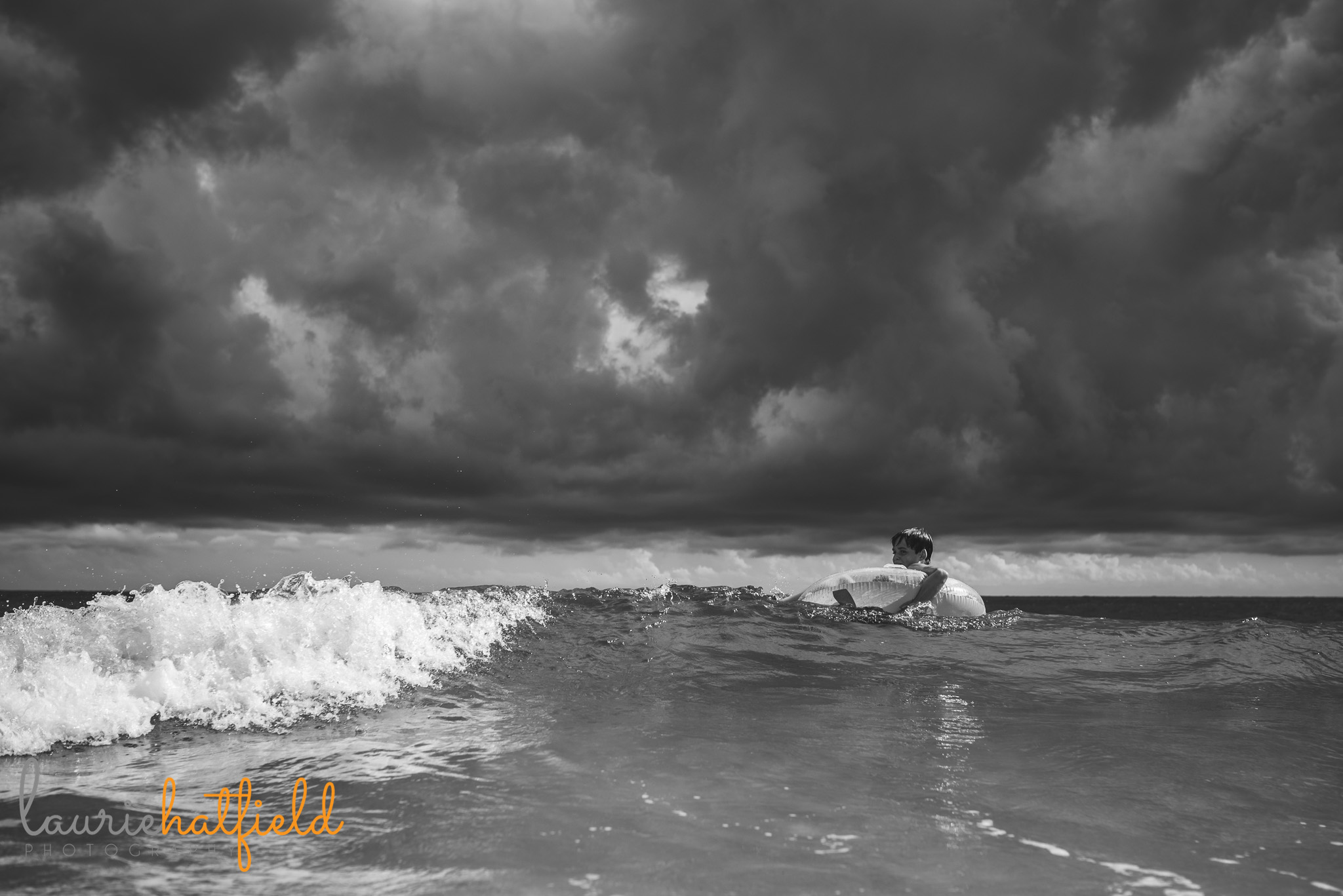 boy on float in ocean with clouds above | Mobile AL child photographer