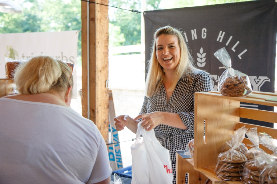 Handing off a bag of deliciousness to a customer, Sarah always has a big smile on her face.