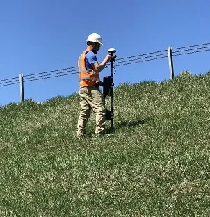 Field Technician collecting measurements of the magnetic field generated by the electric current introduced to the water leaking from the dam.