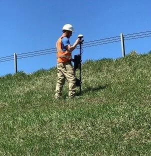 Field Technician collecting measurements of the magnetic field generated by the electric current introduced to the water leaking from the dam.