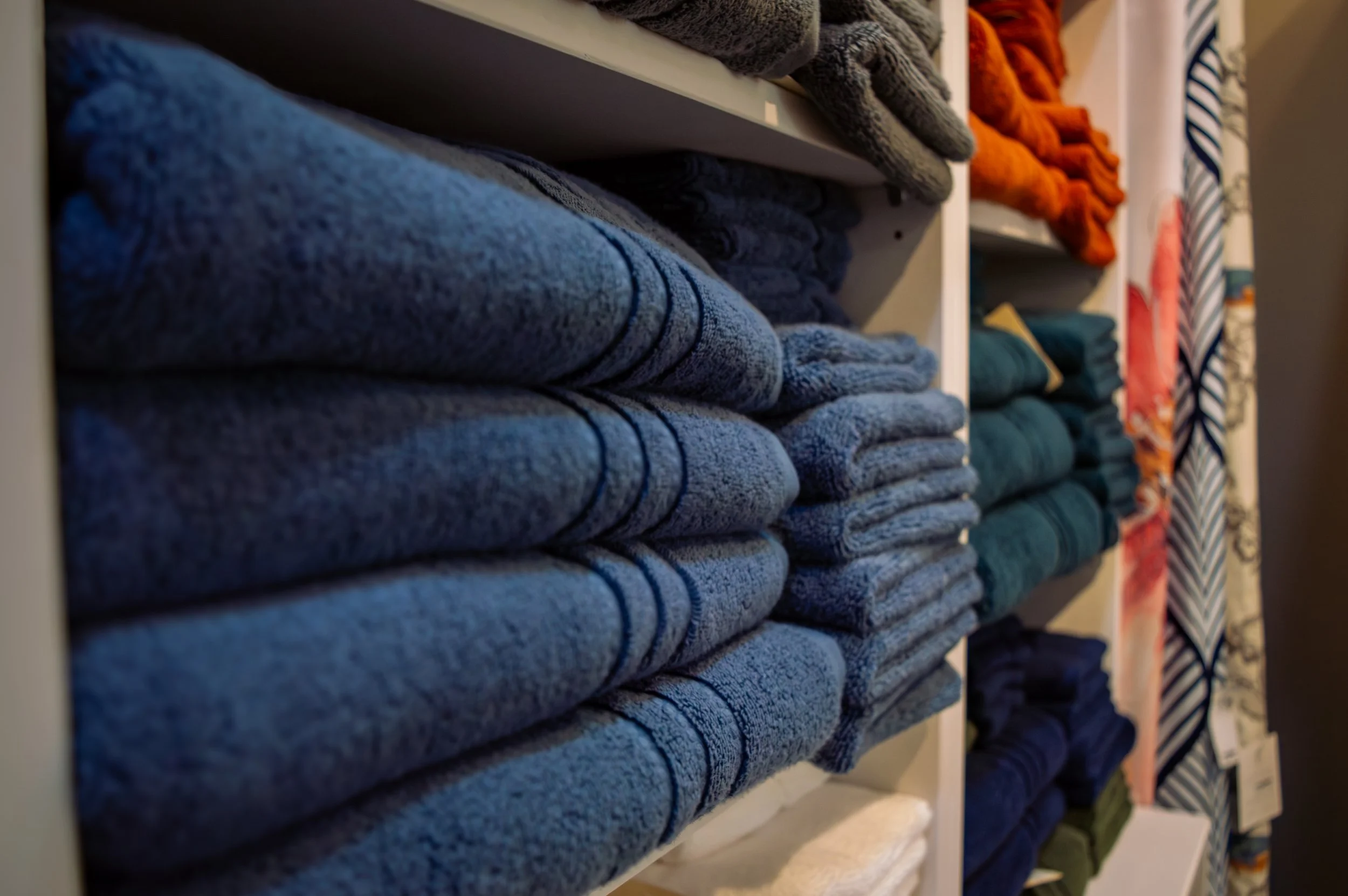 Blue towels, folded and displayed on a white shelf.