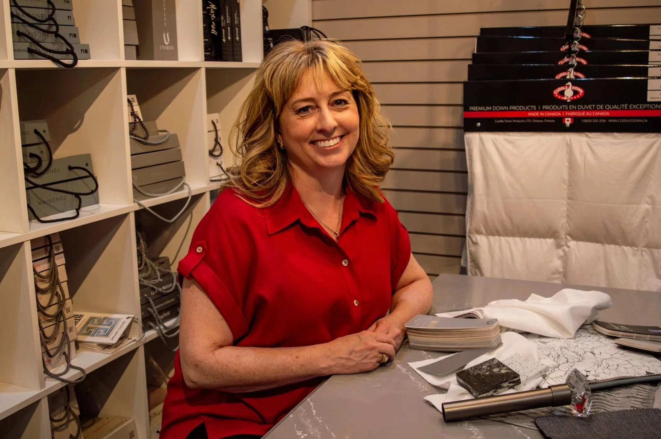 Dara, in a red blouse, leaning over a counter in her store.