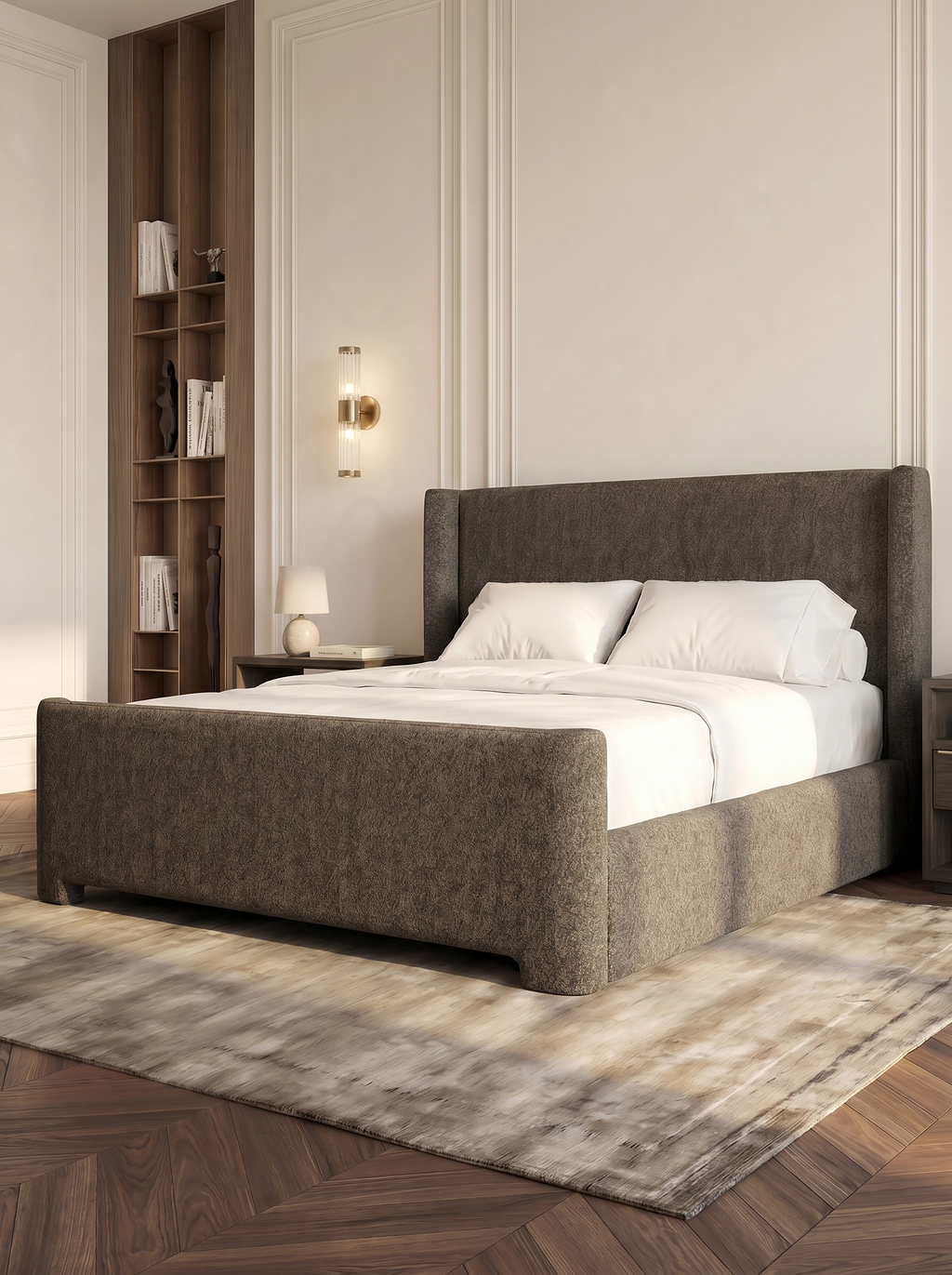 BGrey fabric bedframe, off white duvet and pillows,rug underneath, and wood bookshelf.