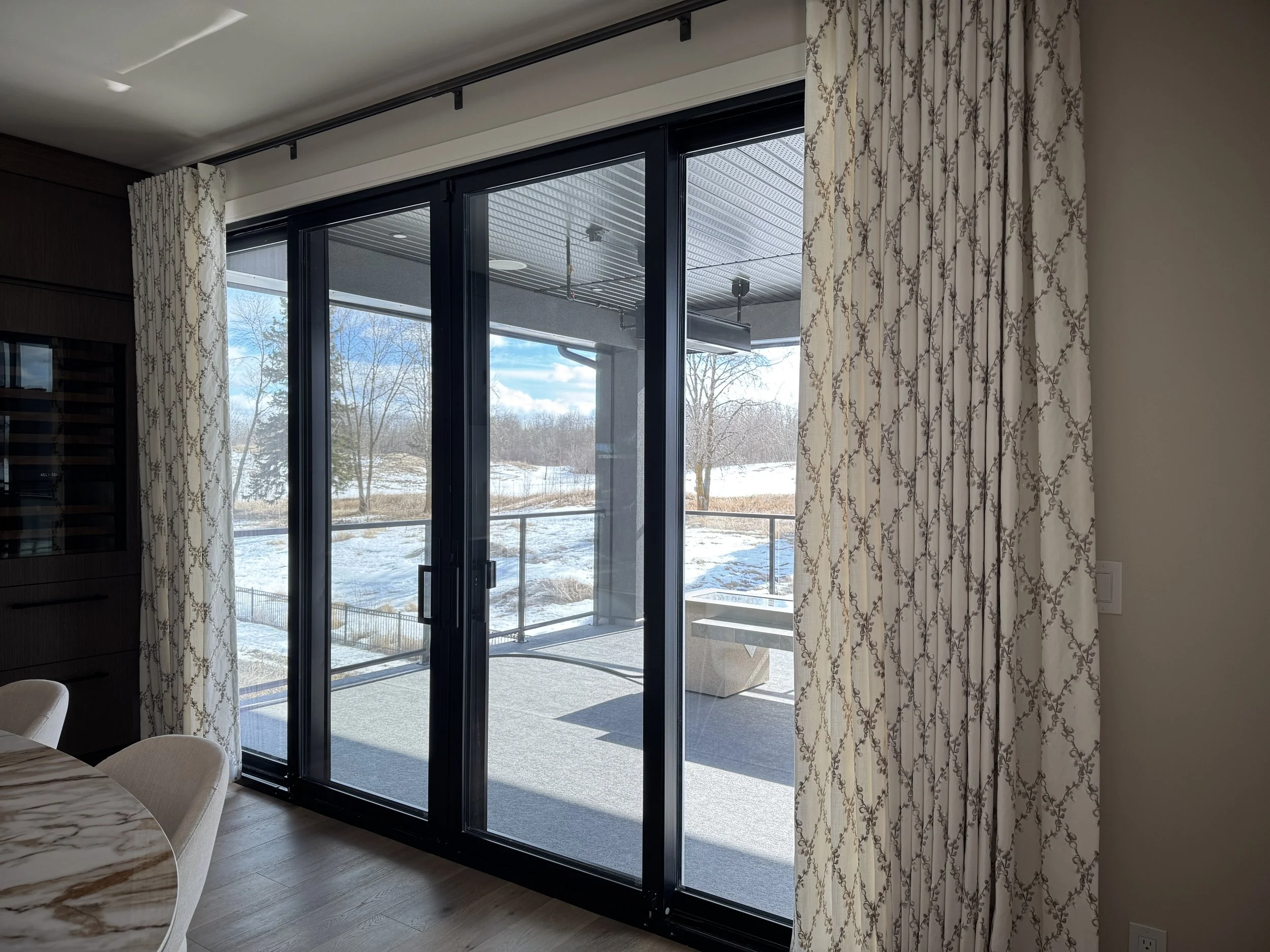 Patterned drapes fitted over a black framed patio door.
