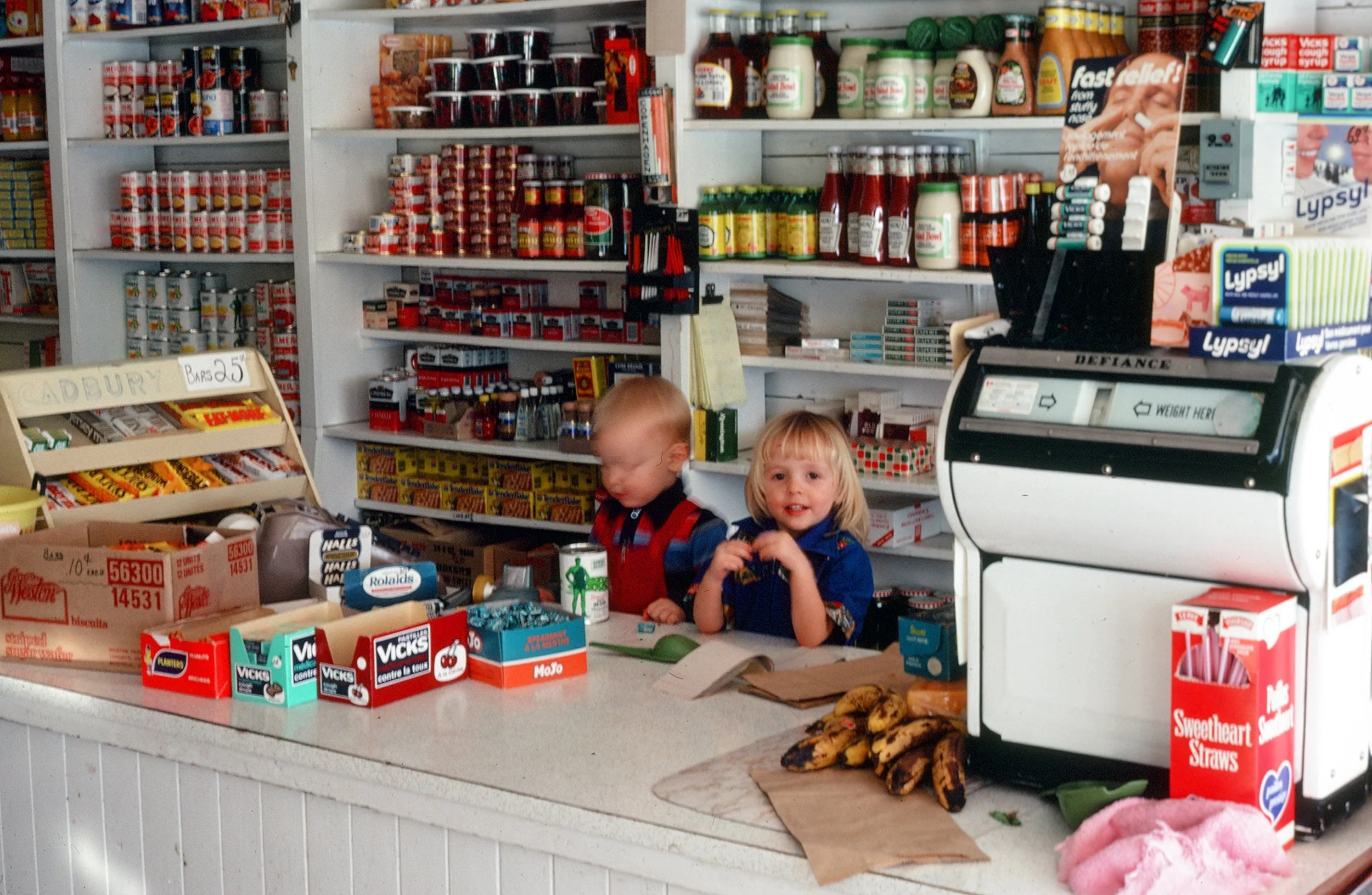 Two small children at the till in a general store, 1970's or 1980's.