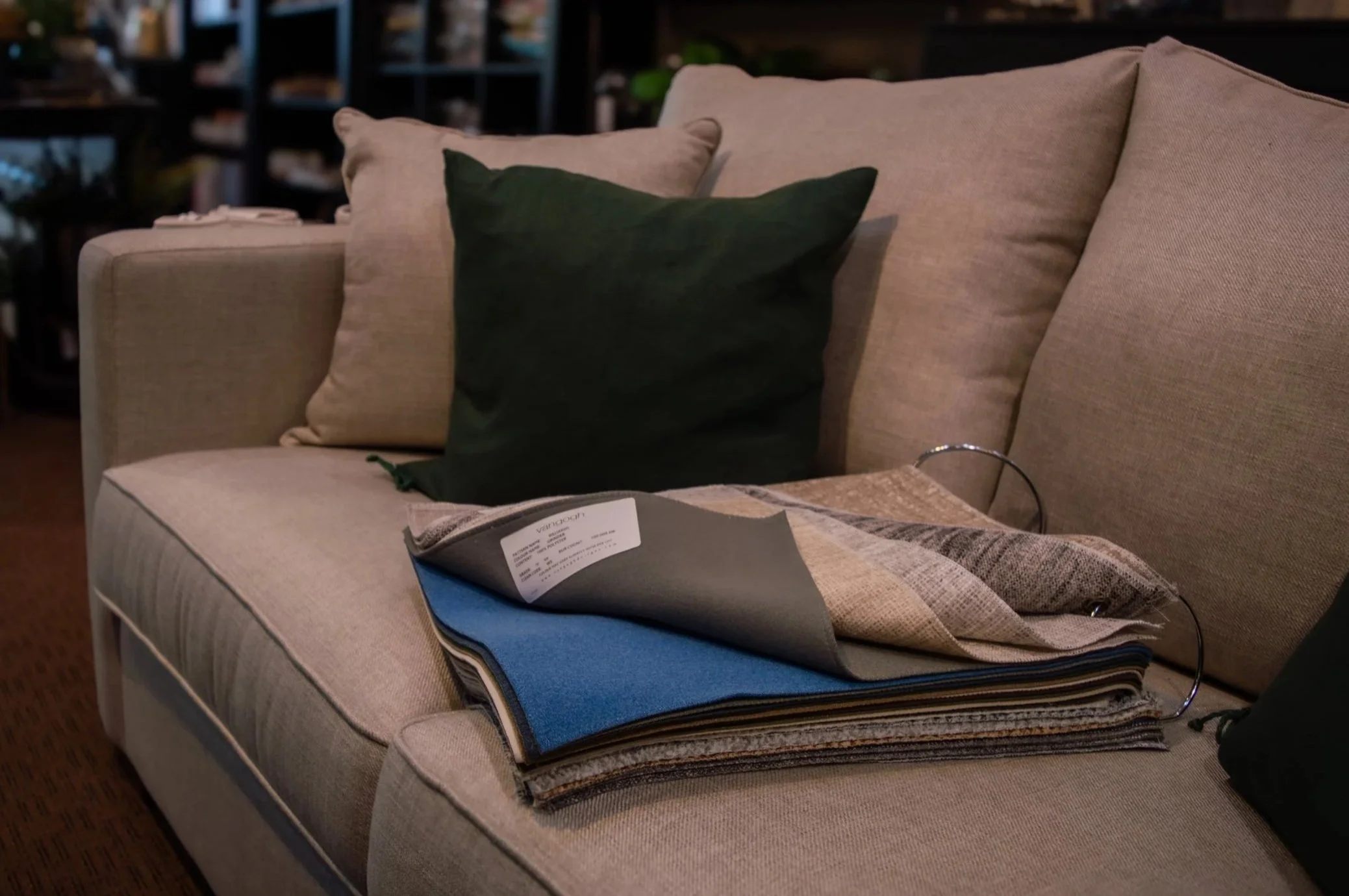 A custom tan couch, with fabric samples displayed on it.