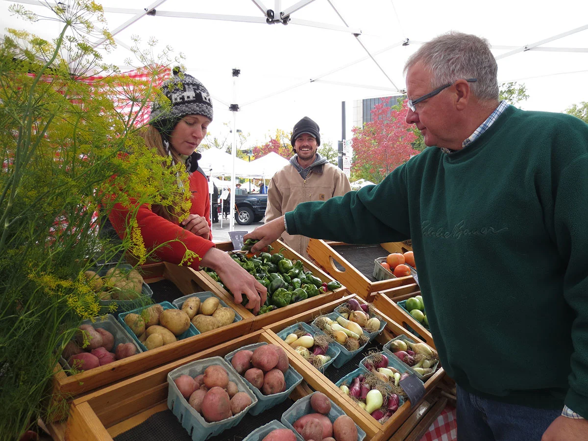  A customer picks out some fresh produce to purchase at this farmer's market booth. 
