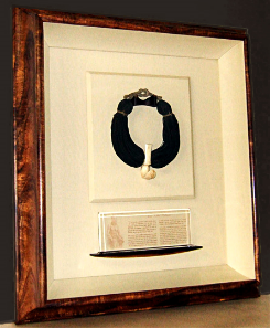 Carved whale tooth strung on thick strands of finely braided human hair Proprietary curly Koa frame with silk back and liner