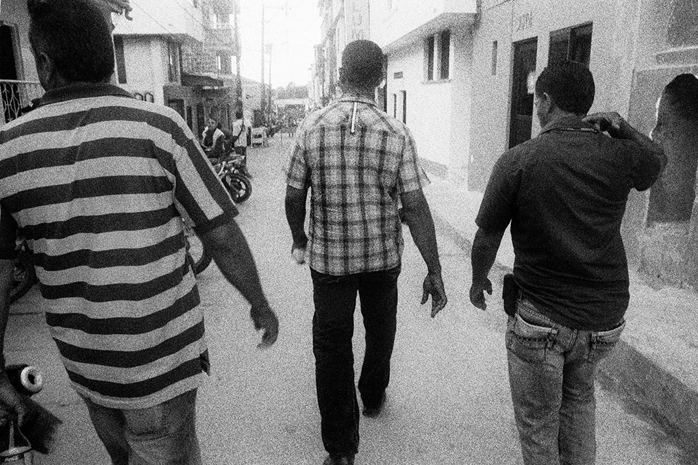   Mr. Dairo Rúa (center), at the time president of the Segovia section of the Sintraminergética miners union, flanked by bodyguards as he walks towards his home in Segovia, Antioquia. Like other leaders of the miners union, Mr. Rúa has been subject t
