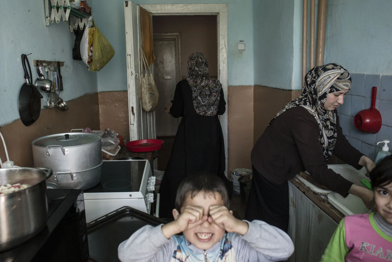 Mariam Muslimova ® and Khadija Adamova are making dinner while their kids play in the kitchen. Both Mariam and Khadija’s families left Crimea after the Russian annexation in February 2014 and moved to a dormitory in a local college in the village of Borynia in the Lviv area of Western Ukraine. Photo by Anastasia Vlasova.