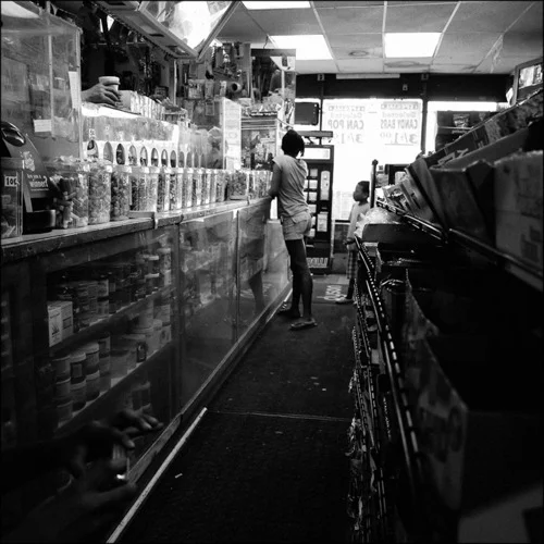 A girl and her brother buy food at the corner store, whose shelves are stocked with a wide variety of chips, candy, and soda. Like many similar establishments, there is no unprocessed or natural food available. Chicago, 2011.