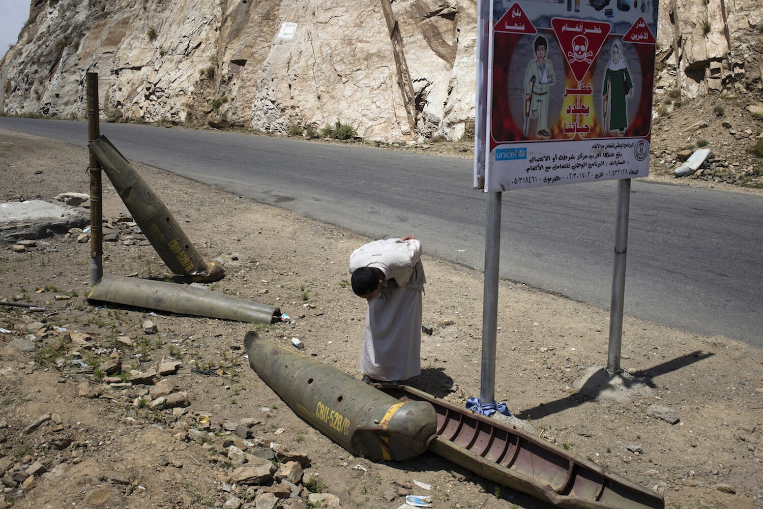  A Houthi supporter looks at the shell of an American-made cluster bomb, many of which still litter the slopes of Saada from the previous wars. 