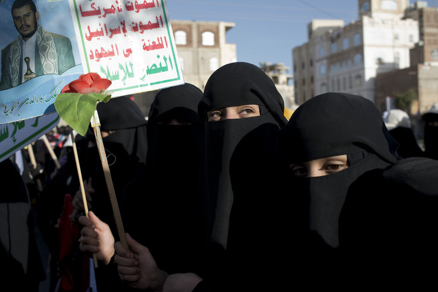  Yemeni women march in support of the Houthis holding up their slogan and an image of the leader, Abdul Malik al Houthi. 