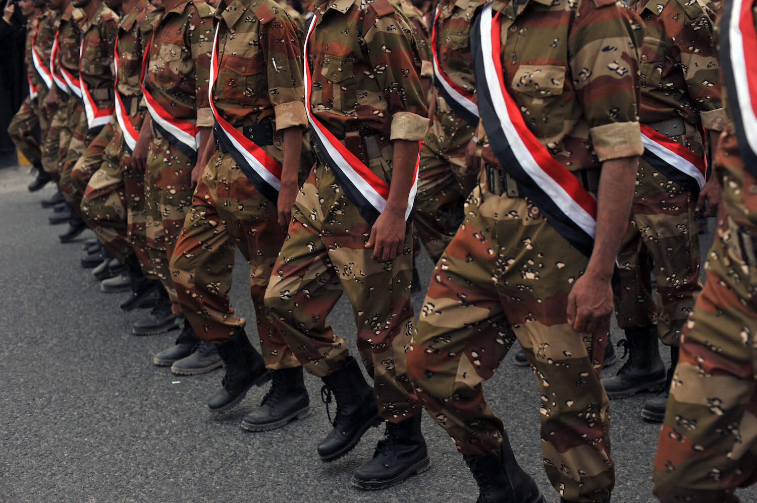  Soldiers draped in the Yemeni flag walk in a march to commemorate the martyrs of the revolution. 