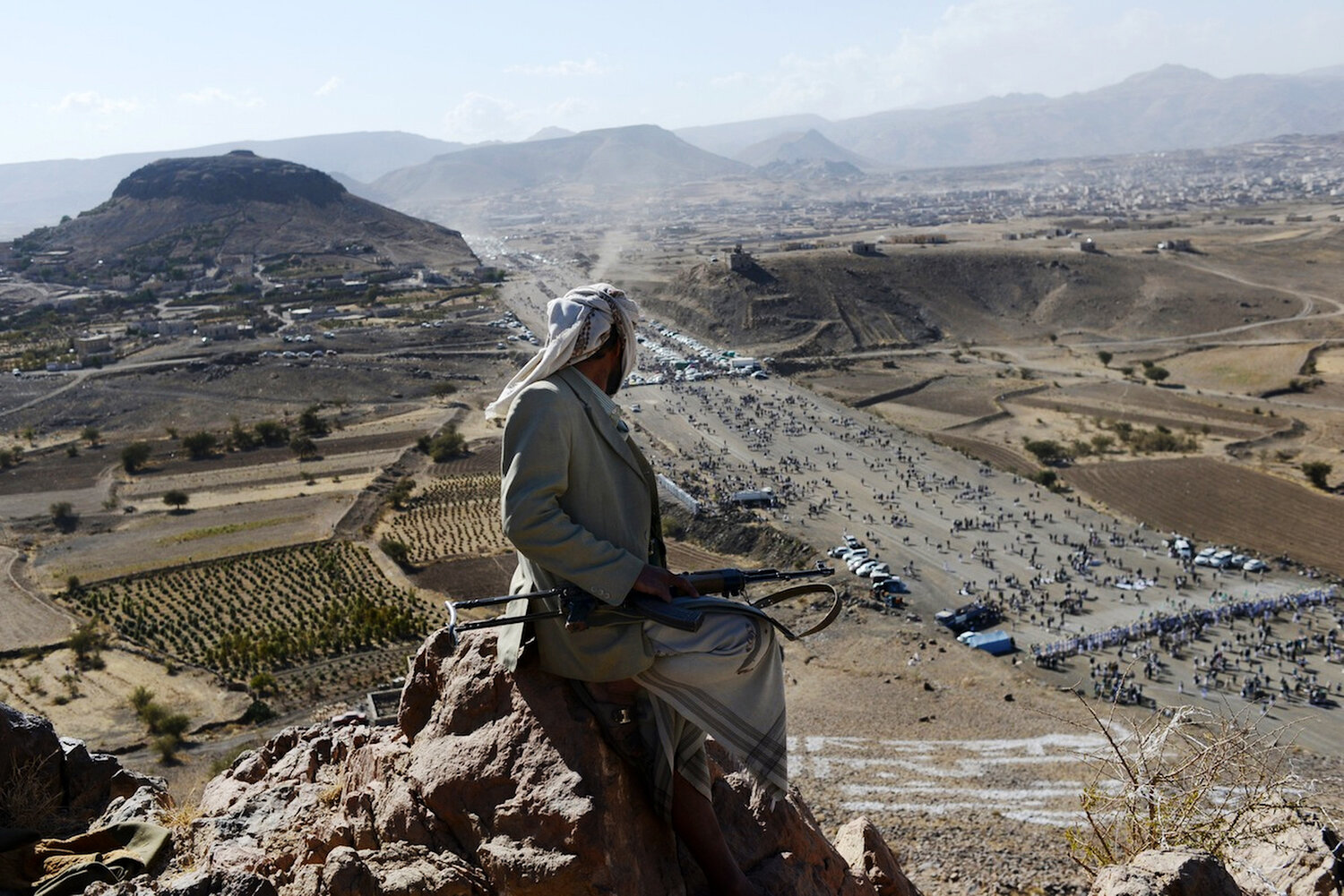  A Yemeni man guards a Houthi gathering from a mountaintop outside of Sana'a. 