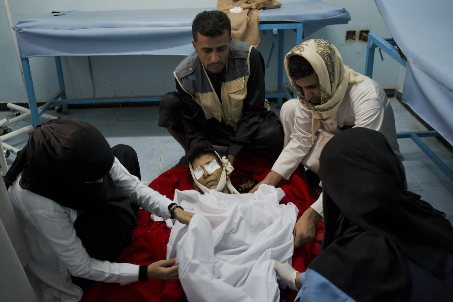  Yemeni men prepare their mother for burial who was killed when a shell hit their home in Taiz. 