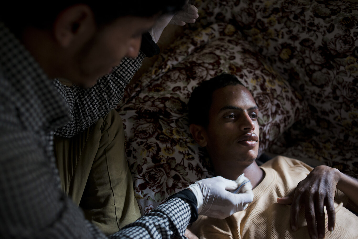  Ahmad Asaba sits as his friend Tareq cleans his wounds on July 4, 2015. Ahmad and his brother Muhammad were severely burned in a car bomb at Qubba al Mahdi Mosque. 