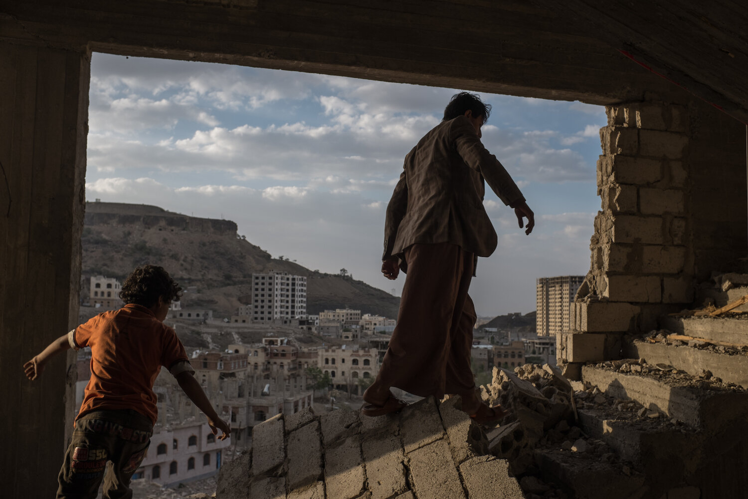  Yemeni brothers climb the broken stairs of an apartment building damaged by airstrikes in the Faj Attan district of Sana'a, Yemen on August 17, 2015. Faj Attan mountain may have a large weapons cache inside, which, if hit by an airstrike, some assum