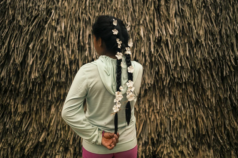  Shaman Jattupa’s granddaughter Yuleivis, 15, stands in front of the Huöttöja communal hut with flowers woven into her braids in the Amazonas state, Venezuela.  
