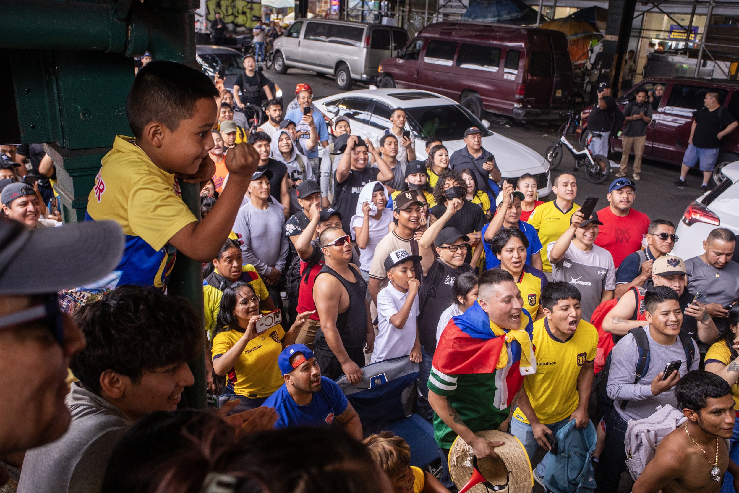  A young Ecuadorian fútbol fan watches alongside cheering fans during Ecuador's 2026 FIFA World Cup match against Germany beneath the elevated Junction Boulevard 7 train on Roosevelt Avenue in Jackson Heights, Queens, June 25, 2026. 