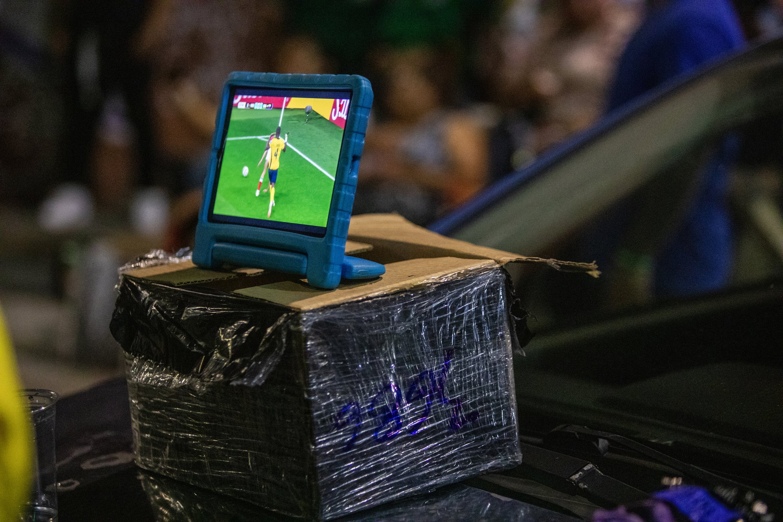  Fans watch the Mexico vs. Ecuador match on an iPad screen propped on a makeshift cardboard box atop a car during the 2026 FIFA World Cup in Bushwick, Brooklyn, July 3, 2026. 