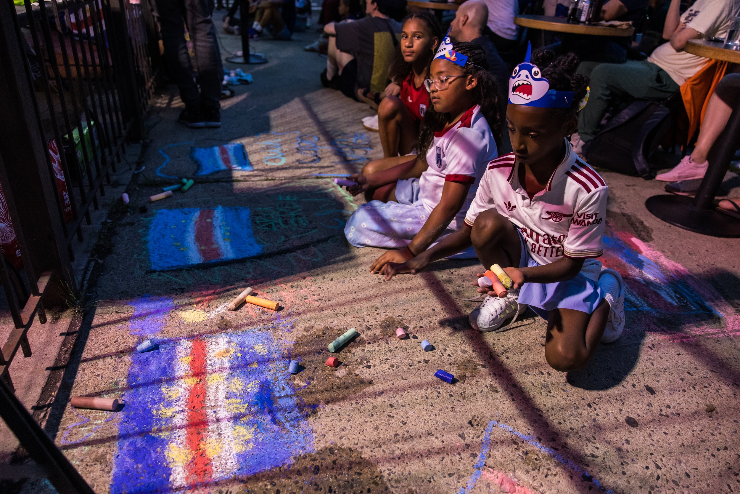  The kids in the crowd hit the pavement with chalk to express their heritage and support. Bed-Stuy, Brooklyn, June 26, 2026. 