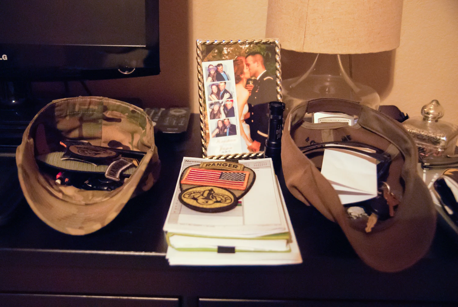 Army Ranger hats and badges on nightstand next to wedding photo.