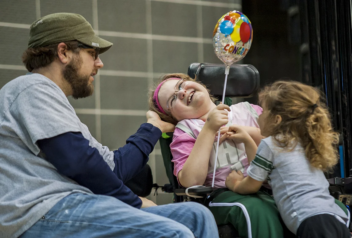  Adyn Bucher, 10, gives a smile to her father Brian Bucher as Adyn's little sister Seneca, 4, tries to play with her during a women’s basketball game in the ConvocationCenter. Adyn is diagnosed with SMA (Spinal Muscular Atrophy) and was recently give