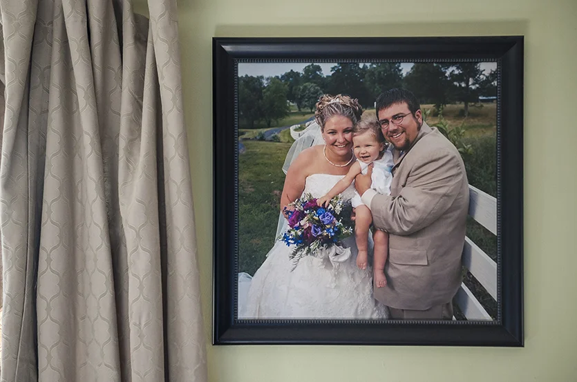  A picture of Lucy, Adyn, and Brian hangs on the wall in Adyn’s living room. 