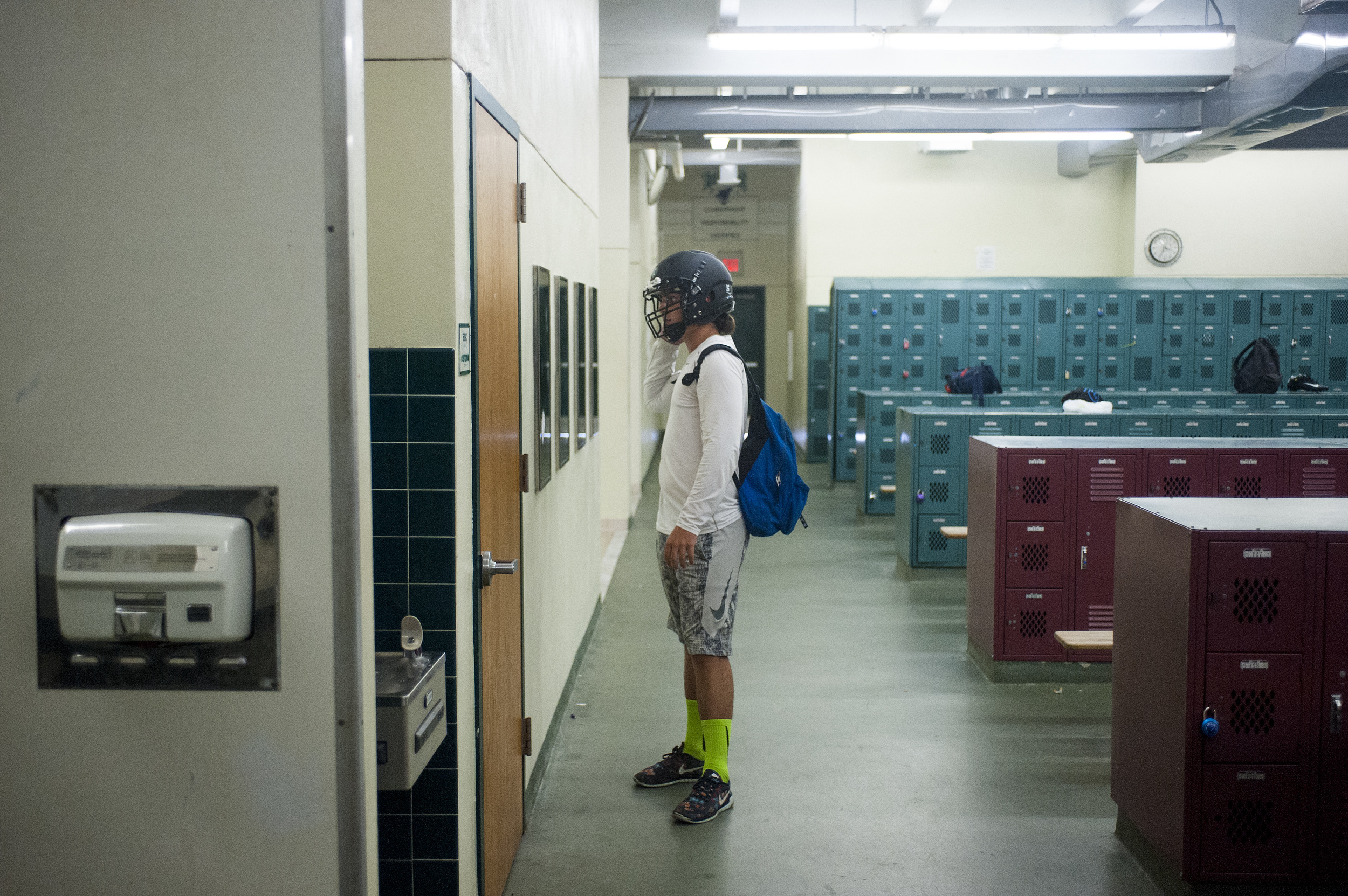 Flanagan high school junior linebacker Lucas Vallee looks at himself with his helmet on in the mirror inside the locker room prior to heading out to the field for the first practice of the high school football season at Flanagan High School on Monda